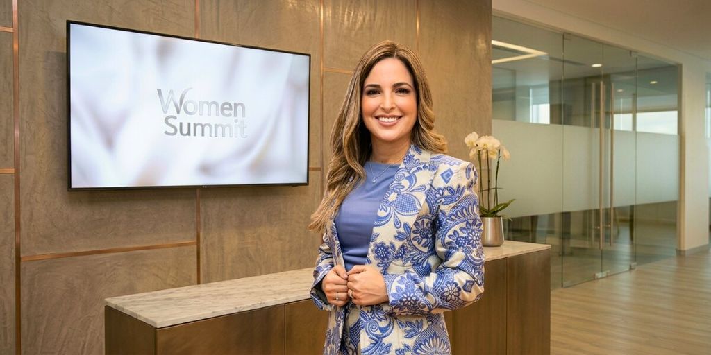 Ariana Acta stands before a large TV screen, representing her impactful journey from the Dominican Republic to global leadership.