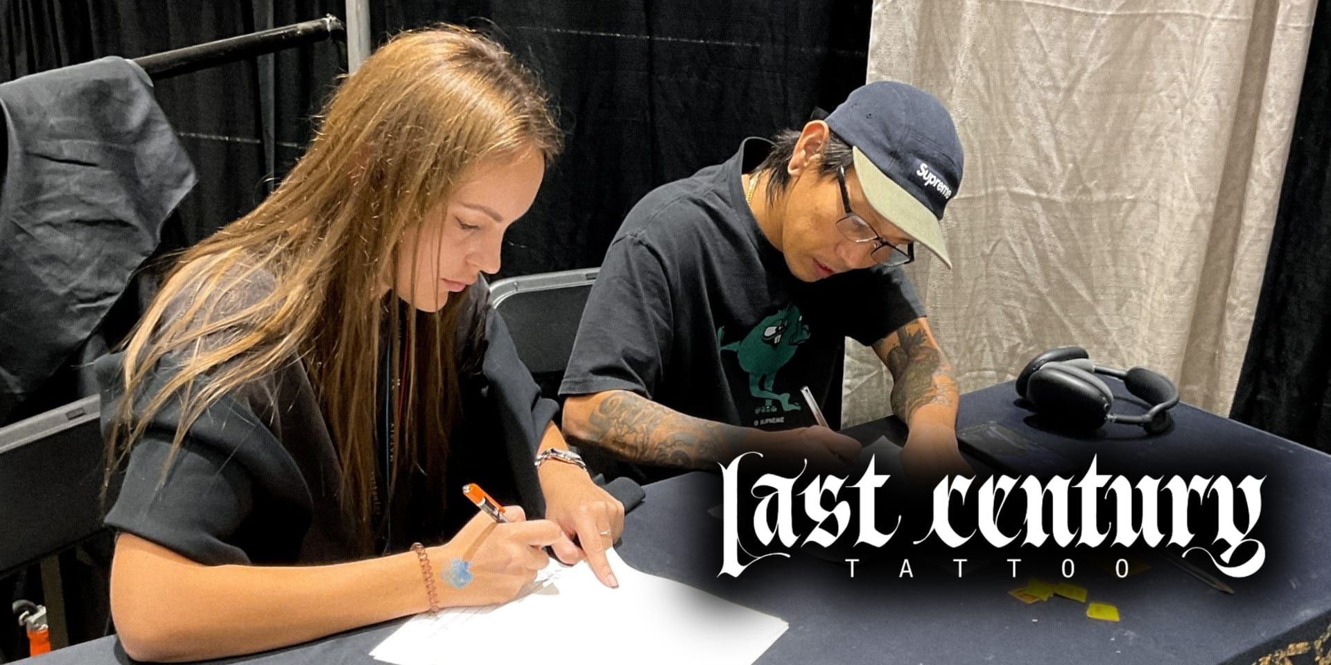 Tattoo artist sketching design with client at Last Century Tattoo studio.