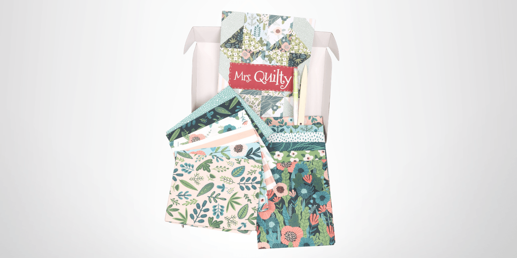 Mrs. Quilty subscription box featuring colorful floral fabric pieces, exclusive patterns, and tools, offering creativity and crafting inspiration.