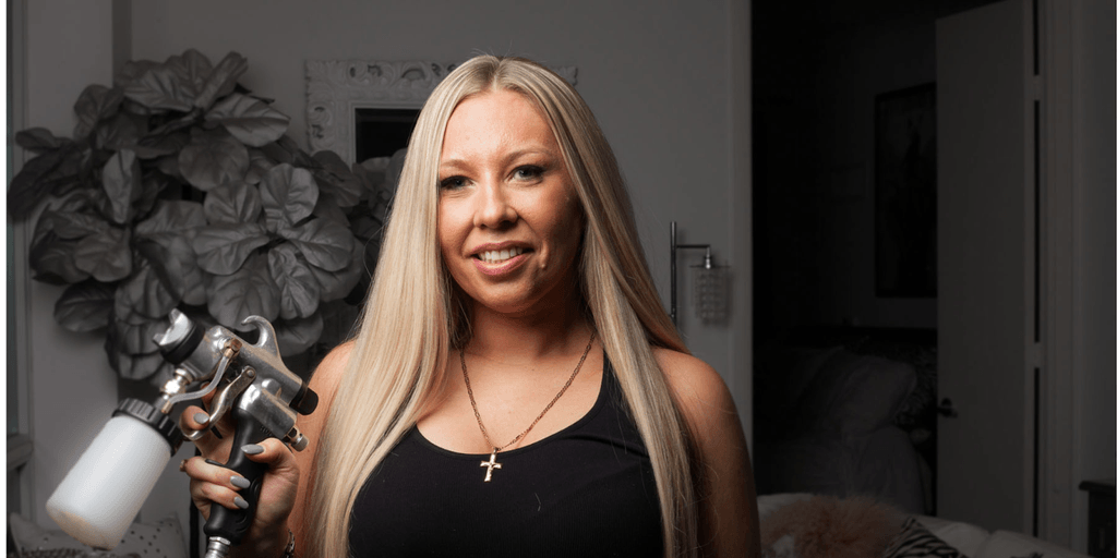 Nicole Hyatt holding spray tan equipment, founder of Tan on the Run mobile spray tan beauty franchise.