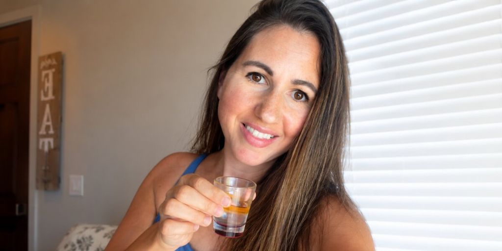 Michelle Unger holds a small wellness shot, representing her informed, test-first approach to everyday wellness.