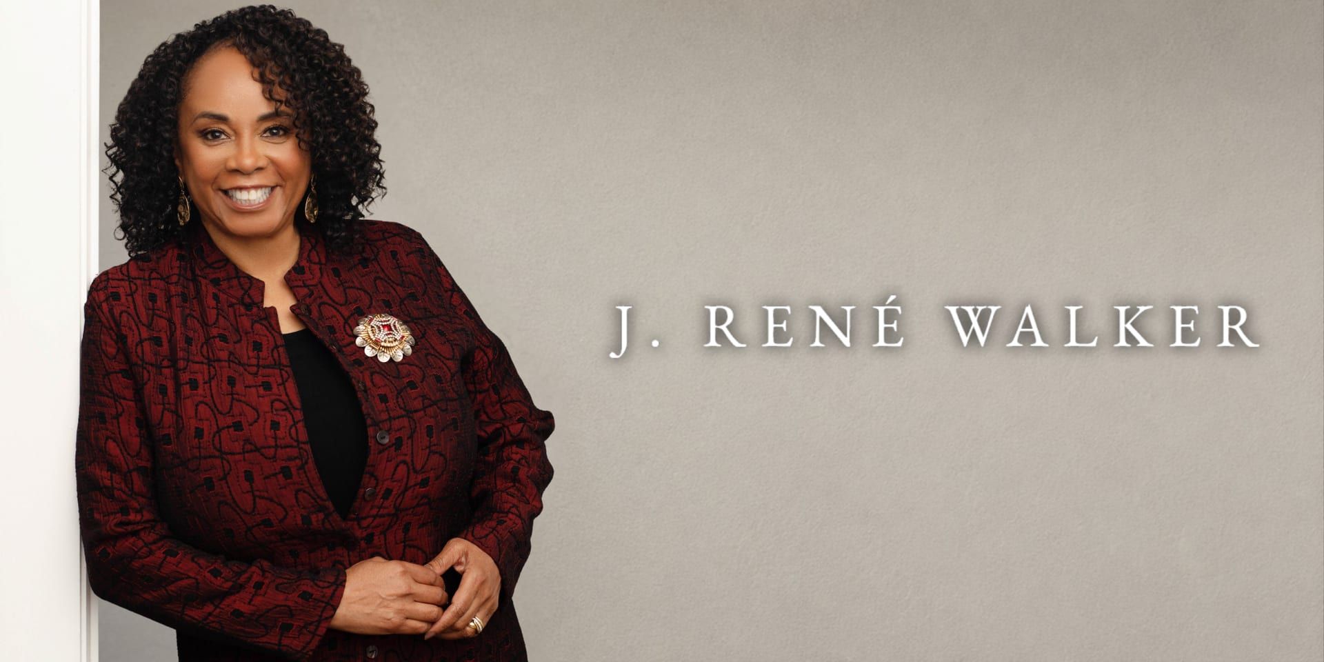 J. René Walker smiles in a burgundy jacket beside her name on a neutral background.