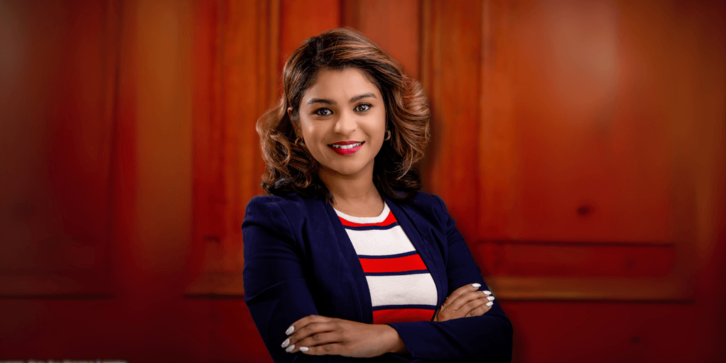 Professional headshot of a woman with a stylish bob haircut, dressed in a striped red, white, and blue top paired with a navy blue blazer, with a warm and approachable expression.