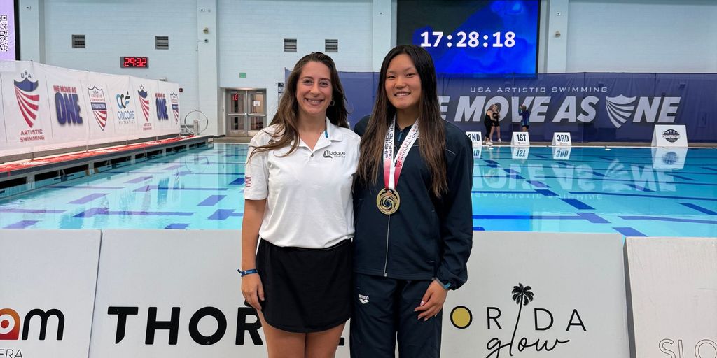 "Irma Davarashvili, artistic swimming coach, poses with her athlete, Isabella Wang, a gold medalist at the 2025 Junior Olympics, celebrating their success at the event in a professional pool setting."