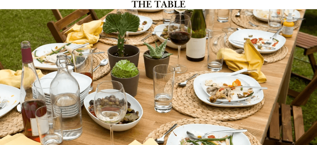 An inviting dining table with plants, glassware, and plates, symbolizing connection and community, perfect for Sandra's faith-driven program.