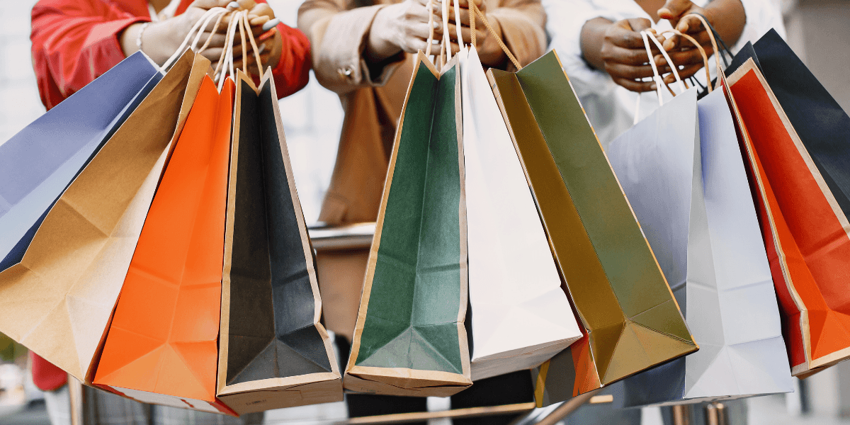 Group of people holding colorful shopping bags in a semi-urban setting