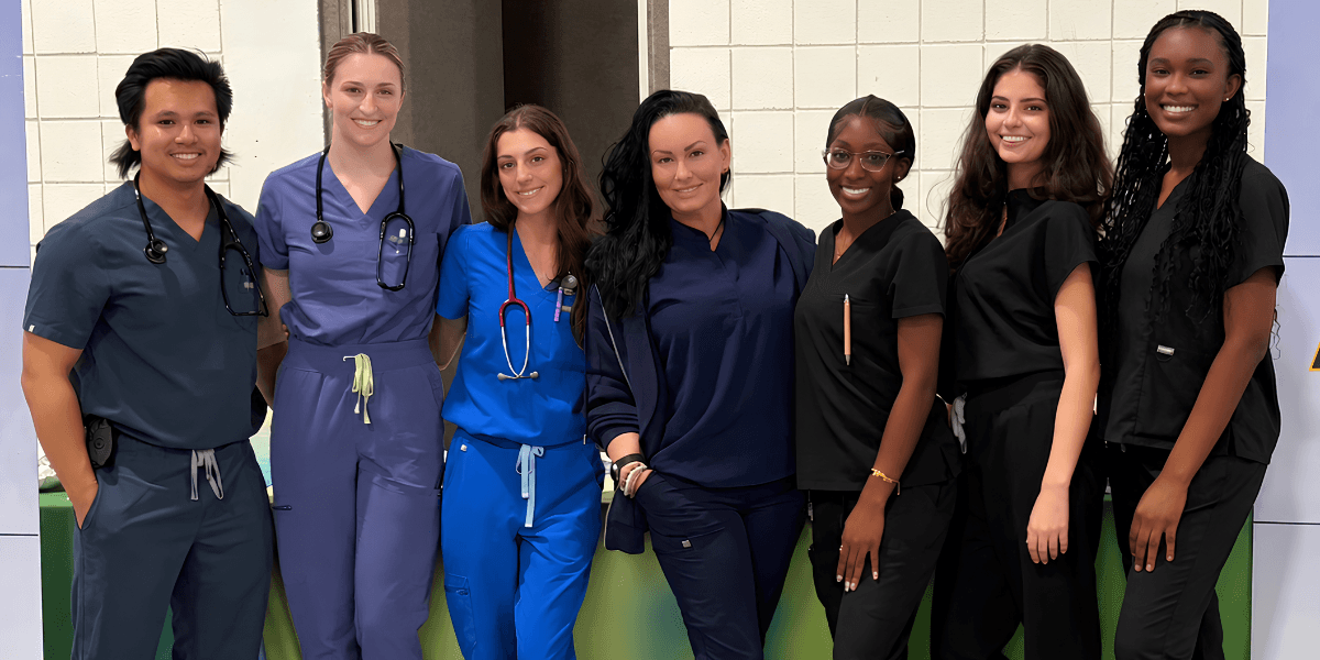 Group of seven healthcare professionals posing together in scrubs and medical attire