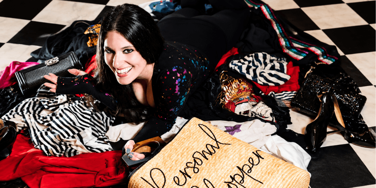 A woman lies on a colorful pile of clothes, smiling with a stylish background.