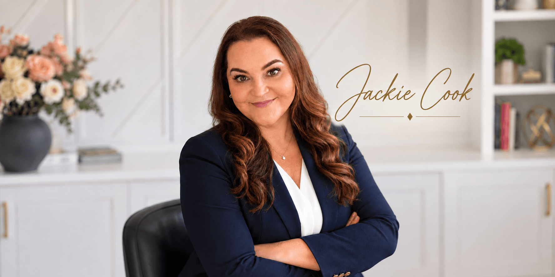 Professional woman in a blazer sitting with arms crossed, smiling at the camera