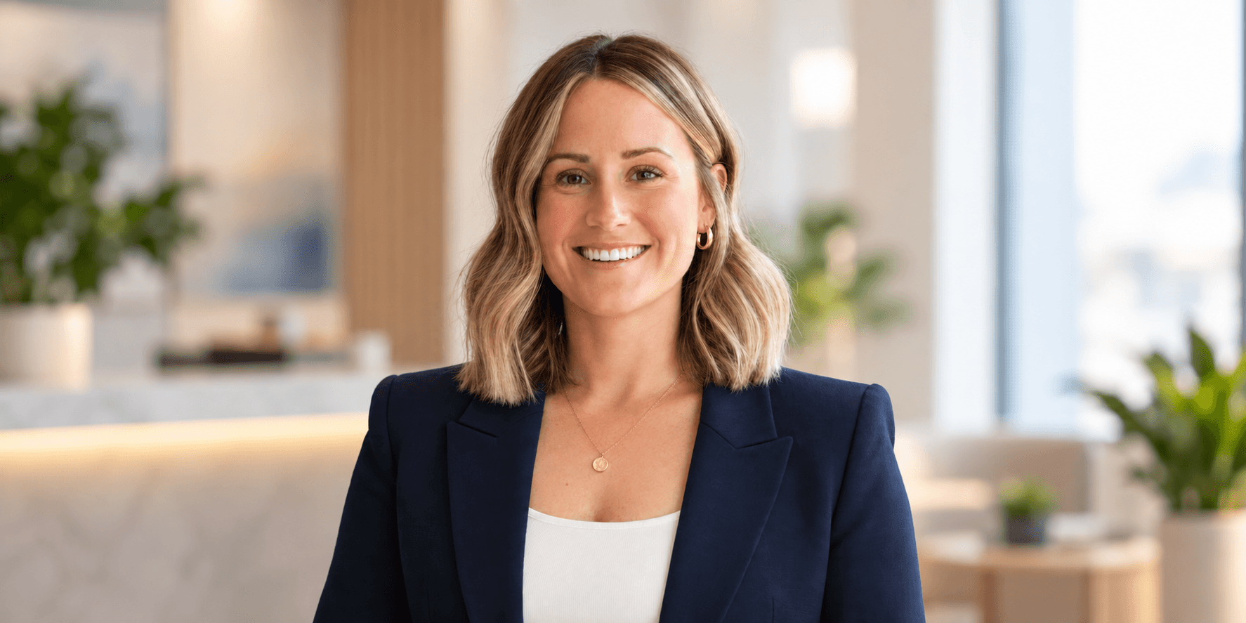 Smiling woman in a navy blazer standing in a modern office space