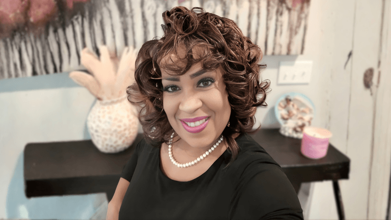 "Debra Savage smiling in a black top with a pearl necklace, representing her comedic ministry and faith-based mission."