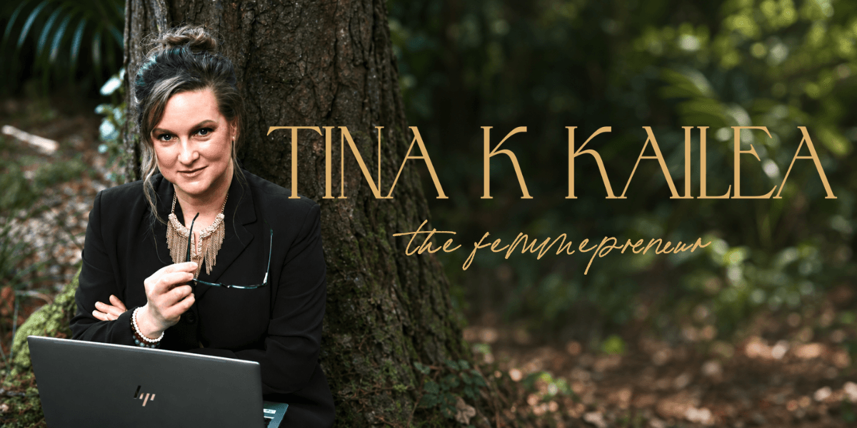 A woman in business attire sitting outdoors, holding glasses near a laptop.