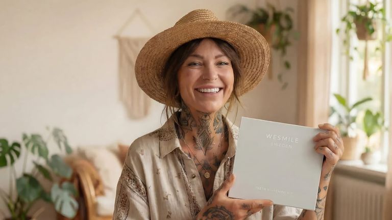 A tattooed woman holds a white box, representing a Swedish brand in the evolving teeth whitening market.