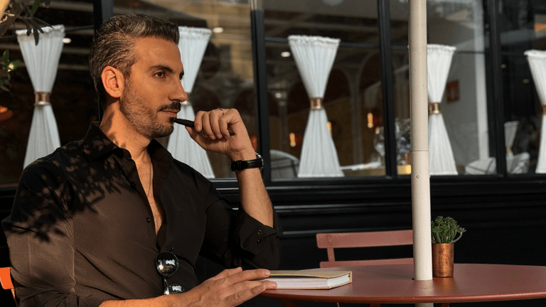 "Johnny Abraham, relationship mentor and author, reflects thoughtfully at an outdoor café, embodying his teachings of emotional growth."