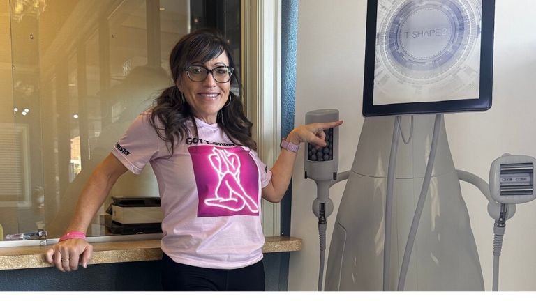 Belinda Preston, founder of Studio B Spa and More, standing next to a T-SHAPE 2 device, smiling.