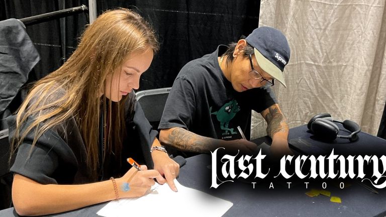 Tattoo artist sketching design with client at Last Century Tattoo studio.