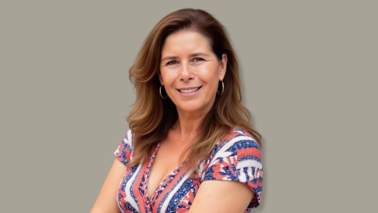 Portrait of executive leadership advisor Helena Demuynck smiling, wearing a patterned dress against a neutral background.
