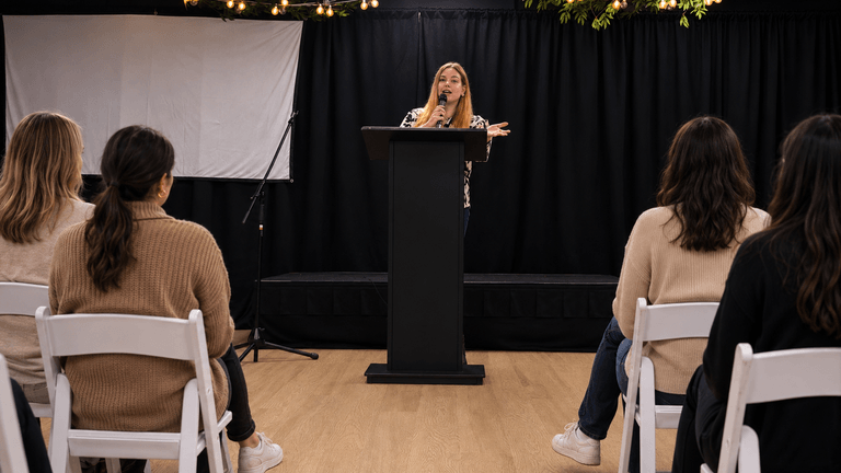 Woman speaking at a podium during a women’s empowerment or storytelling event.