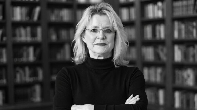 Sandra K. Griffith in front of bookshelves with arms crossed.