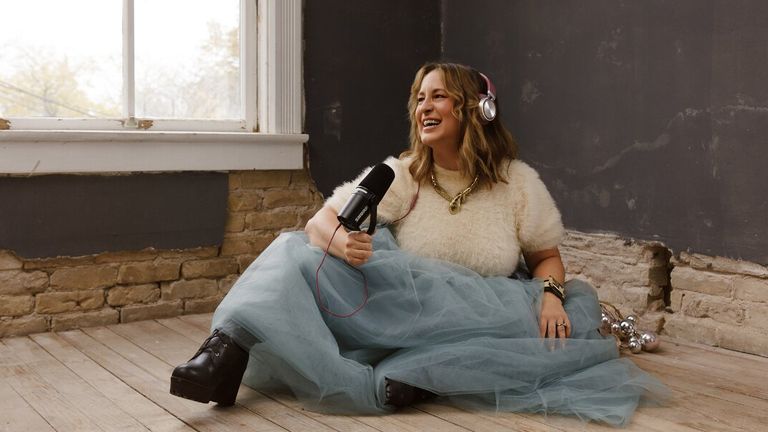 Kimberly Spencer seated with headphones and microphone, speaking in a relaxed podcast-style setting.