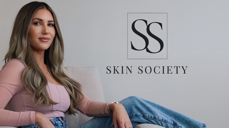 Sally Delory seated beside the Skin Society logo in a promotional brand portrait.