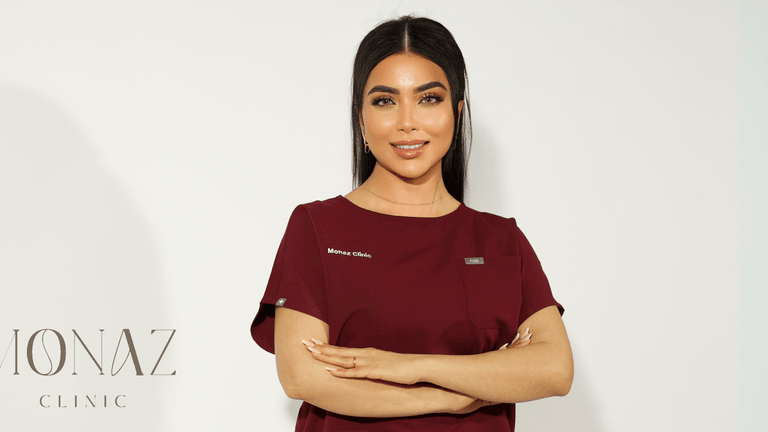 The image shows a luxurious aesthetic clinic with soft lighting, elegant white furniture, and subtle floral decor, creating a serene, upscale environment.
