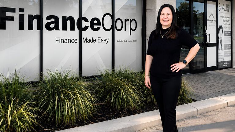 Tracey Franco standing outside FinanceCorp office with company signage visible in the background.