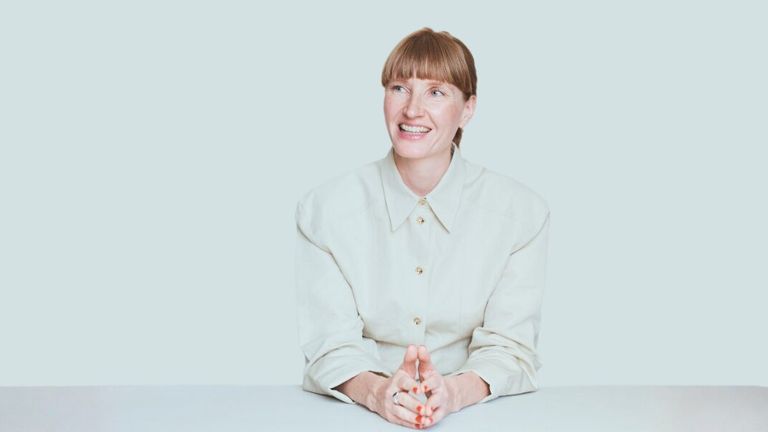 Helene Christensen, founder of Eksakt, smiling and seated, embodying calm and clarity as she discusses personal transformation.