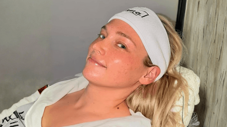 Woman wearing headband reclines during facial treatment, glowing skin in serene spa setting.