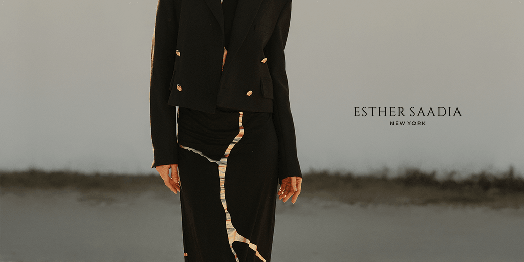 Model wearing a black tailored jacket and flowing skirt with metallic detailing, photographed outdoors for Esther Saadia New York.