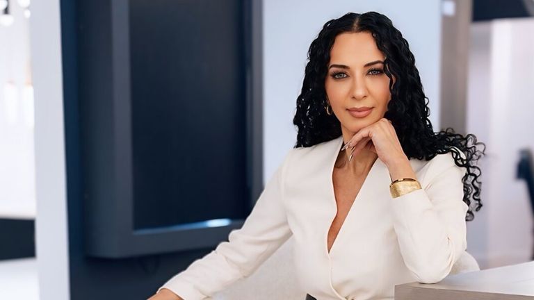 Klaudia Zinaty, founder of Women Empowerment Awards, exuding confidence in a white blouse, embodying leadership and empowerment