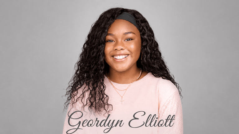 Smiling young author Geordyn Elliott wearing a pink shirt and cross necklace against a gray background.