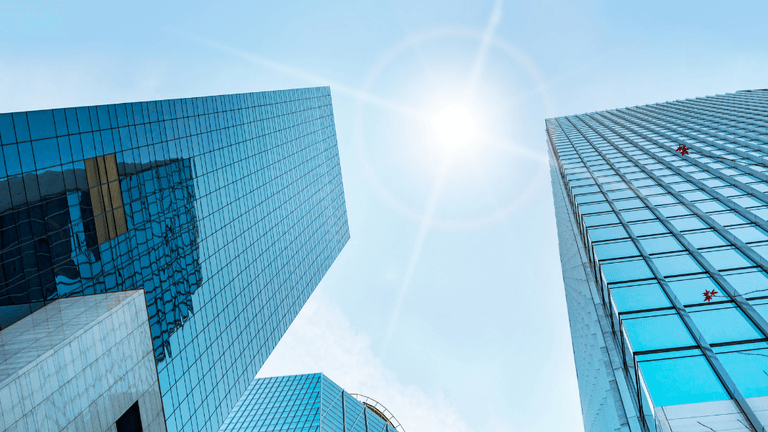 Modern glass office towers beneath a bright blue sky, representing business innovation and corporate growth.