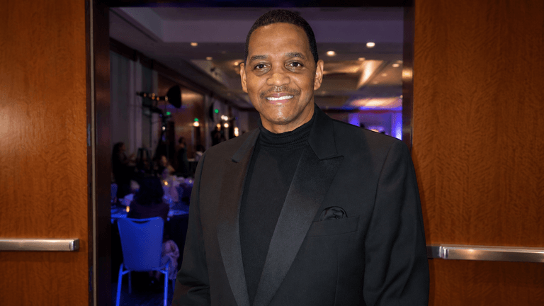 Prof. Robert Stewart smiles at a formal evening event in a black tuxedo and turtleneck.”