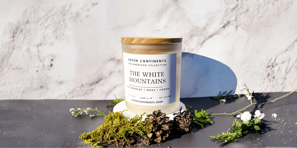The image showcases a Seven Continents candle, "The White Mountains," symbolizing the brand's focus on travel-inspired scents crafted from clean ingredients.