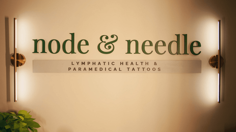 Signage for "node & needle," a wellness studio offering lymphatic health and paramedical tattoo services for healing and empowerment.