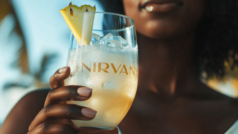 “Woman holding branded Nirvana cocktail, showcasing the company’s premium wellness-focused RTD product and luxury, refreshing lifestyle experience in a tropical setting.”