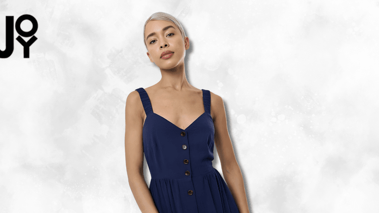 "Fashionable model wearing a navy blue dress with button details, posing confidently with a clean, bright background, promoting joy and confidence in style."