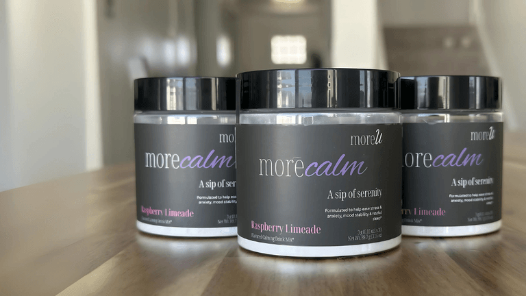 Two containers of morecalm Raspberry Limeade calming drink mix on a wooden surface, with the label 'A sip of serenity' visible.