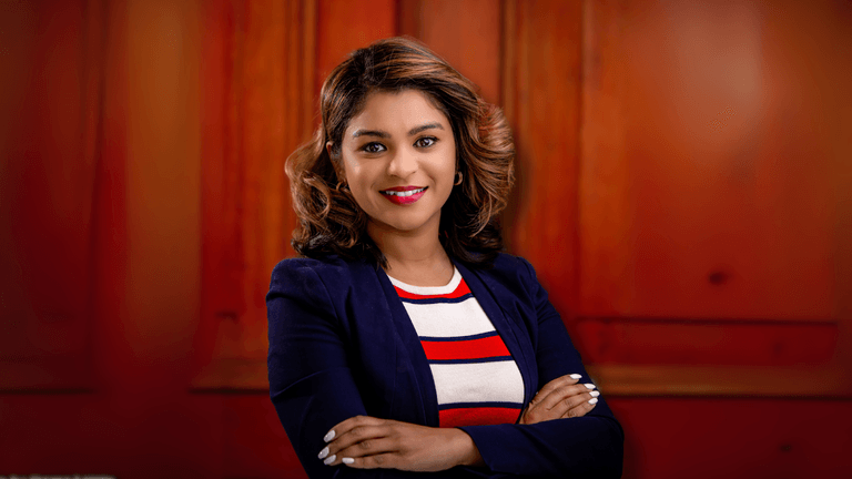 Professional headshot of a woman with a stylish bob haircut, dressed in a striped red, white, and blue top paired with a navy blue blazer, with a warm and approachable expression.