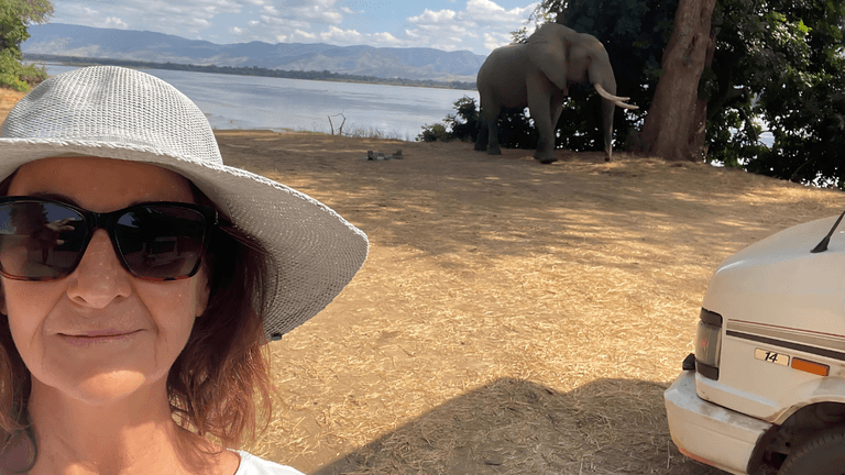 A woman enjoys a scenic moment with an elephant while reflecting on gender and storytelling.