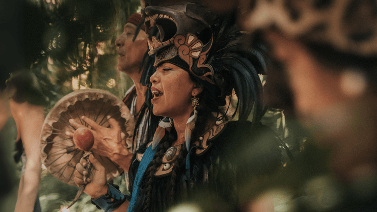 People in traditional attire performing a ceremonial ritual with drums in a lush jungle setting at Lunita Jungle Retreat.