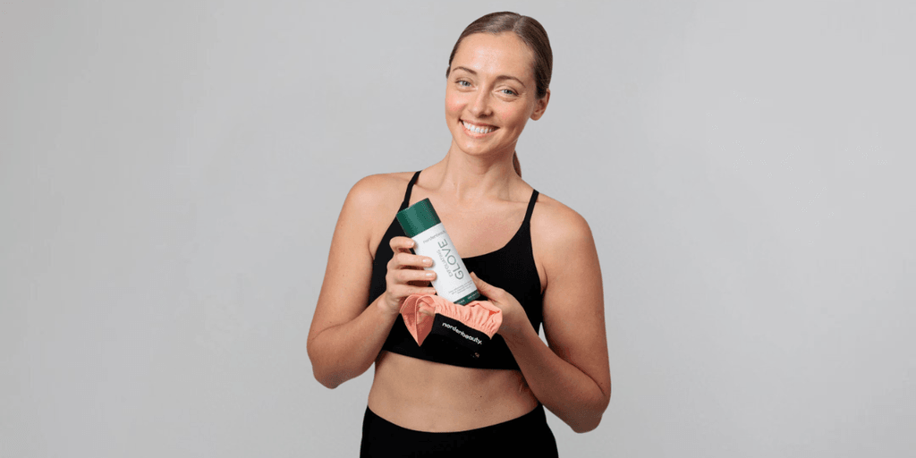 "Smiling woman in athletic wear holding the Nordenbeauty Turkish Silk Exfoliating Glove, promoting smooth, glowing skin."