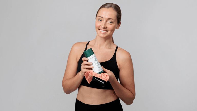 "Smiling woman in athletic wear holding the Nordenbeauty Turkish Silk Exfoliating Glove, promoting smooth, glowing skin."