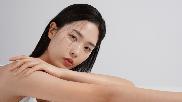 A young woman resting her arms on a surface, gazing thoughtfully at the camera