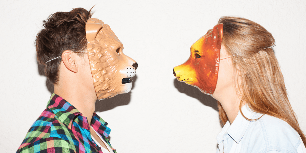 Two people wearing animal masks face each other against a plain background