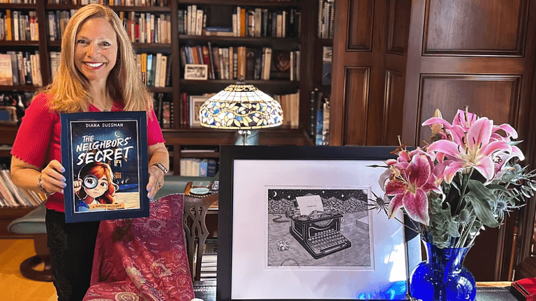 Woman holding a book titled "The Neighbor's Secret" beside flowers and a framed drawing