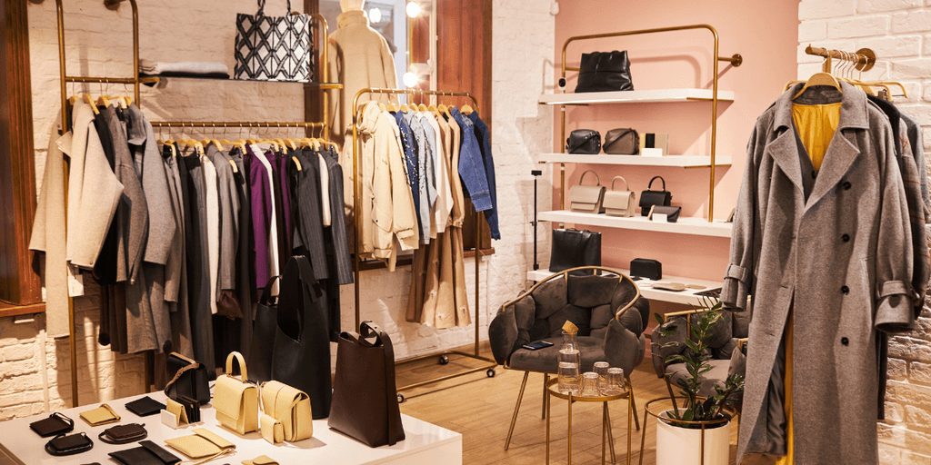 Fashion boutique interior featuring clothing racks, handbags, and cozy seating area