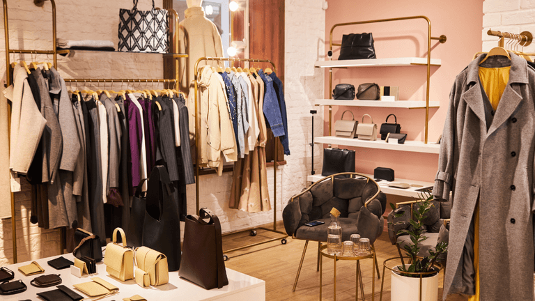 Fashion boutique interior featuring clothing racks, handbags, and cozy seating area