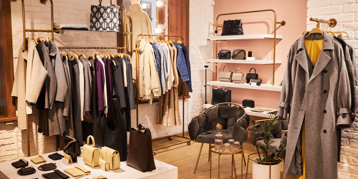 Fashion boutique interior featuring clothing racks, handbags, and cozy seating area